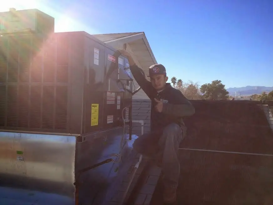HVAC technician performing AC Tune-Up on a rooftop unit in Chocolay